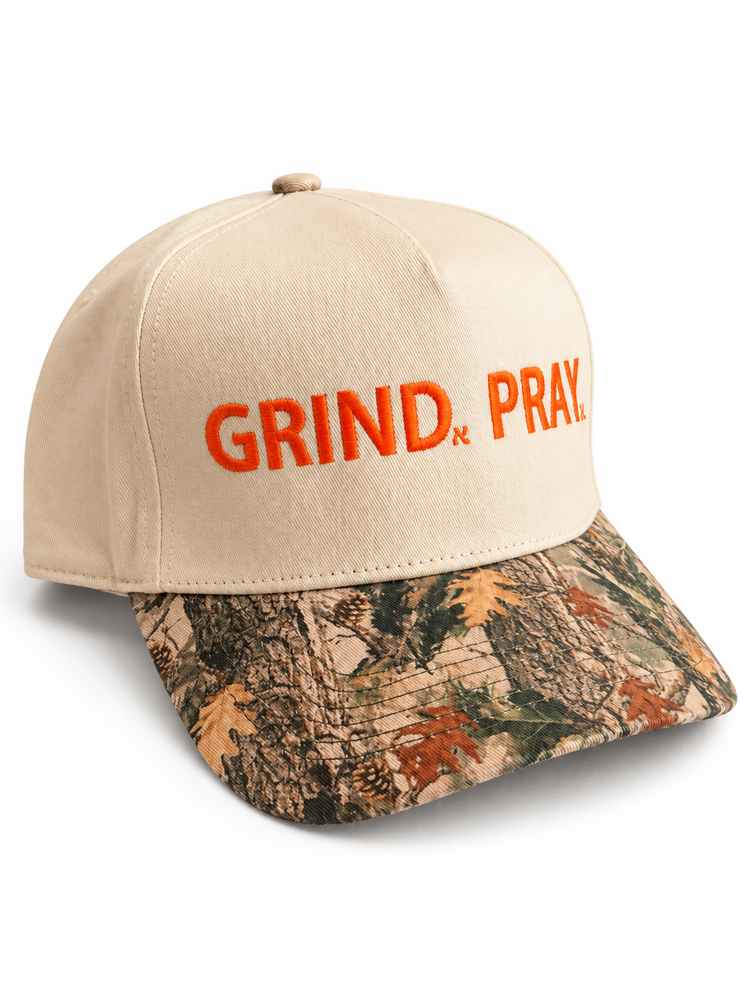 Cream Grind.Pray. cap with orange embroidered lettering and a woodland camouflage brim